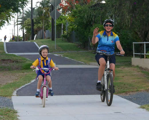 School child and adult riding bikes on path