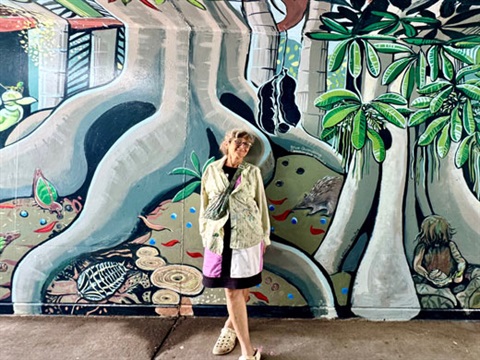 The artist Kate Brunner standing Infront of the mural