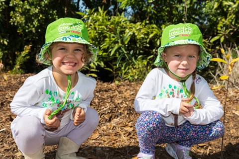 Two young children planting trees.
